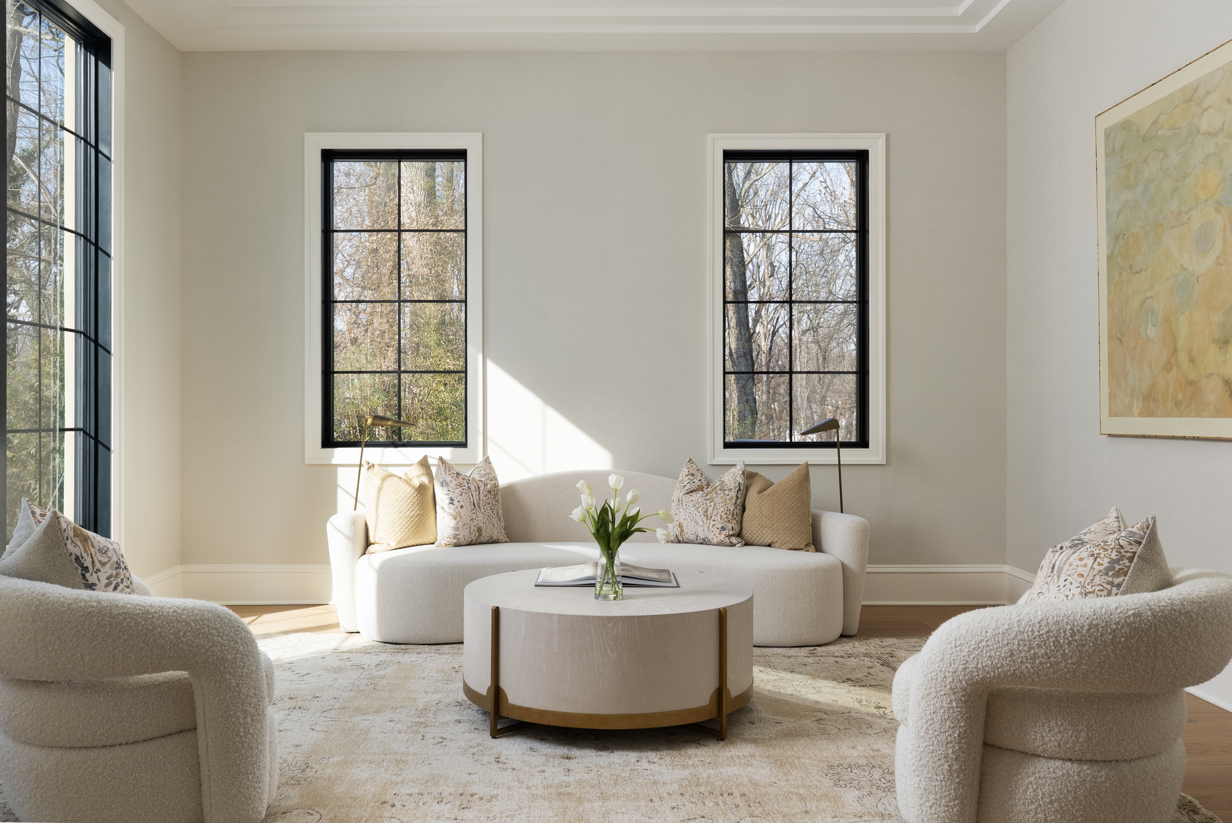 Sun-filled sitting room with bouclé armchairs and black steel-frame windows