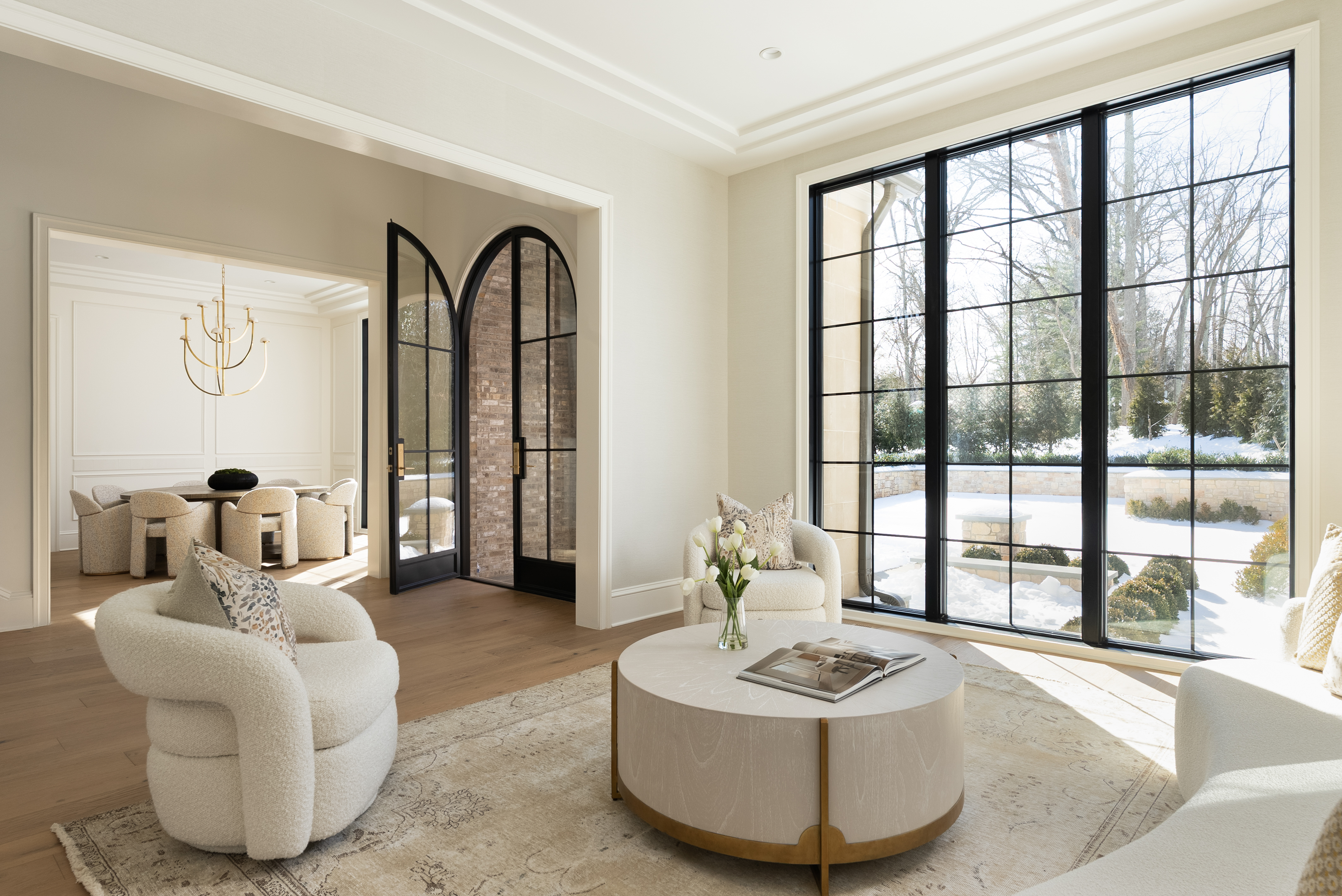 Open living area with arched iron doors, floor-to-ceiling steel windows, and natural light