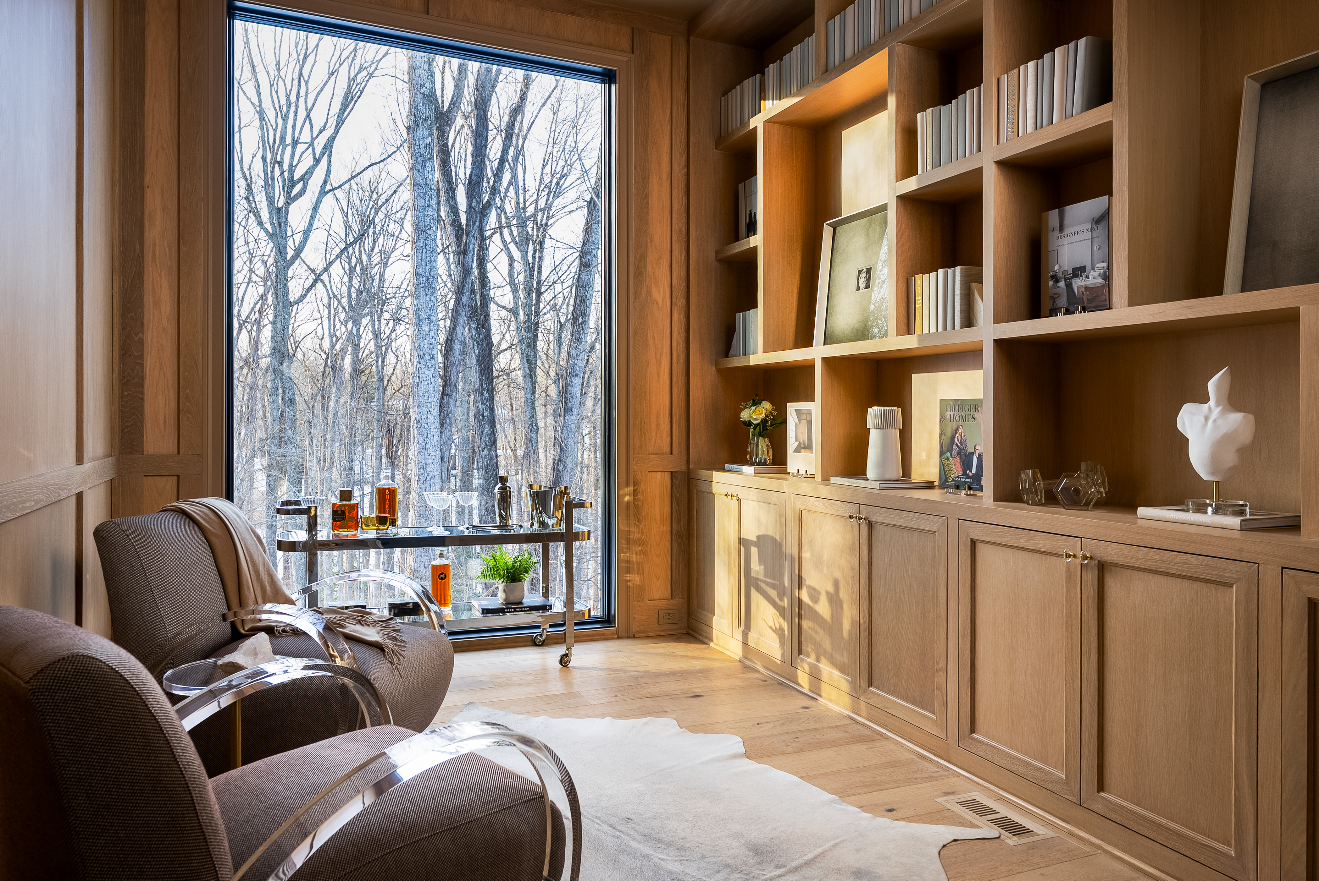 Oak-paneled library with floor-to-ceiling window overlooking winter woods