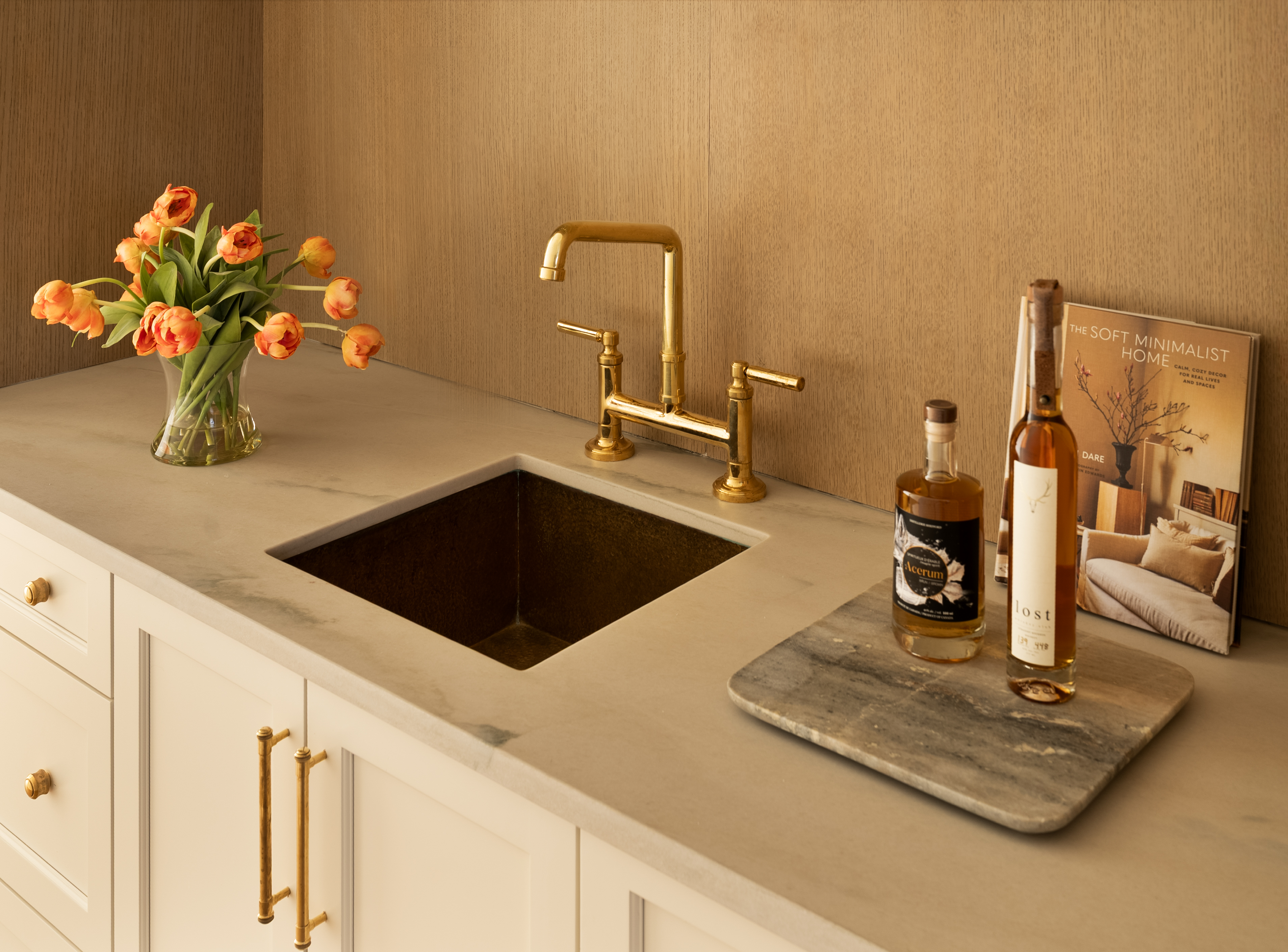 Custom wet bar with fluted oak cabinetry, marble countertop, and brass fixtures