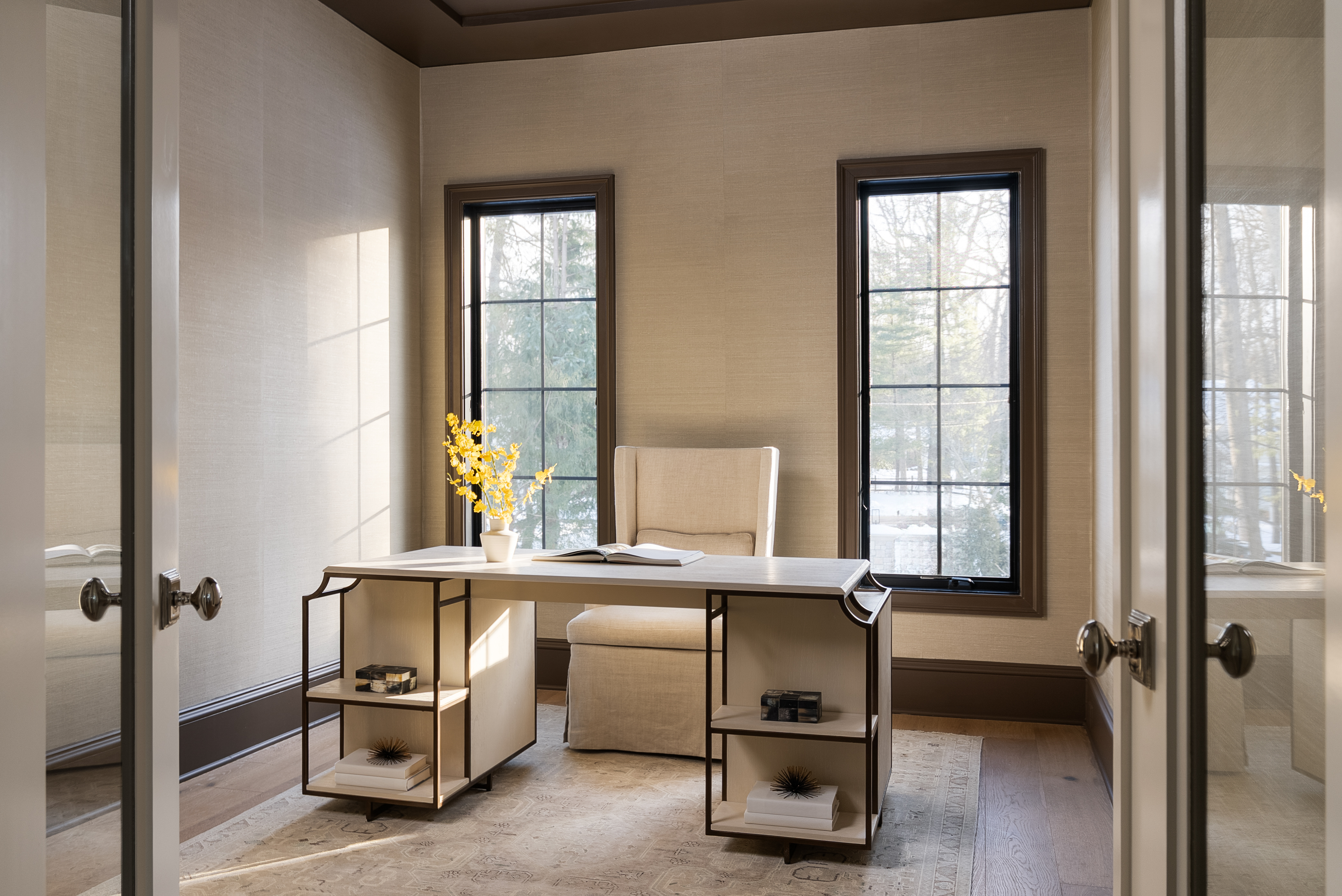 Private home office with iron-frame desk and black steel windows overlooking wooded lot