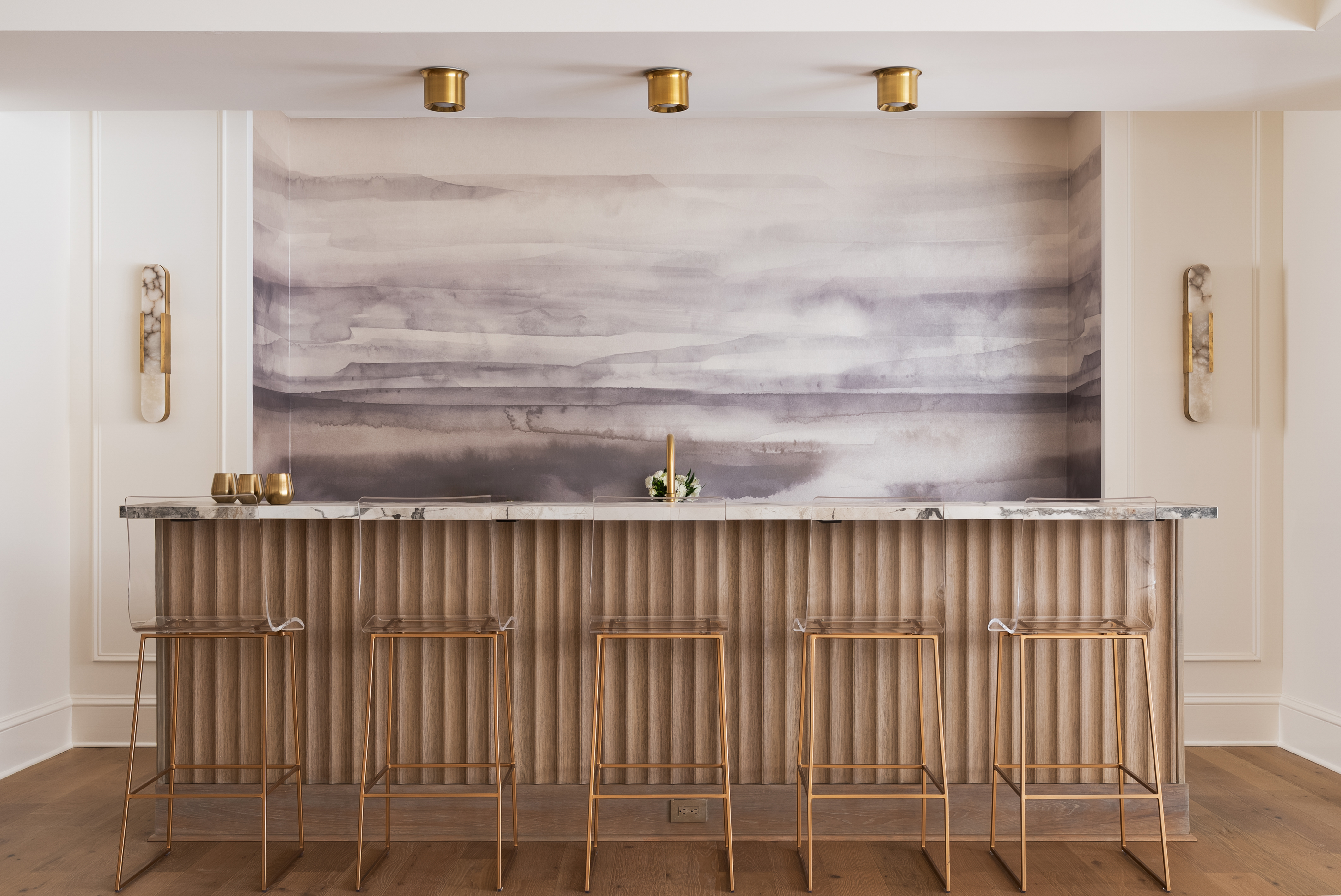 Custom wet bar with marble counter, fluted oak panels, and watercolor mural backdrop